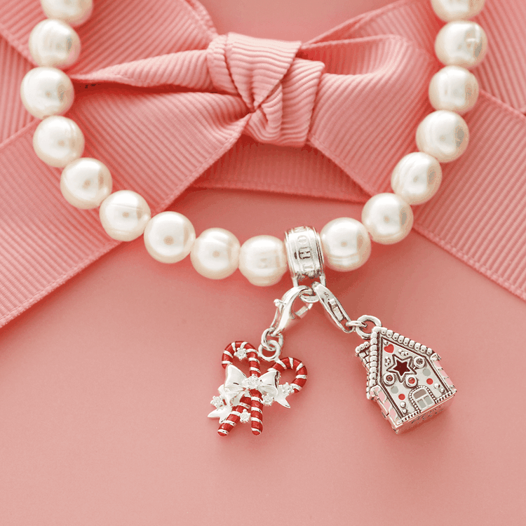 Thomas Sabo karácsonyi charmok cukorpálcával és házikóval Thomas Sabo karácsonyi charmok: piros-fehér cukorpálca pár és részletes mézeskalács házikó függő ünnepi stílusban.