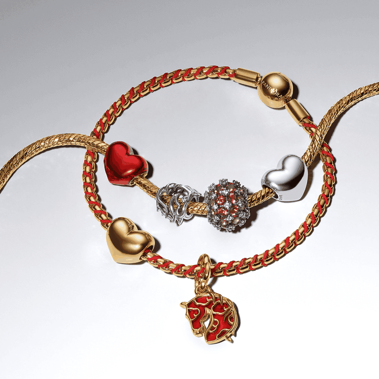 Pandora karkötő romantikus charmokkal Pandora karkötő arany tónusban, szív alakú és figurális charmokkal, gazdag részletekkel és romantikus hangulattal