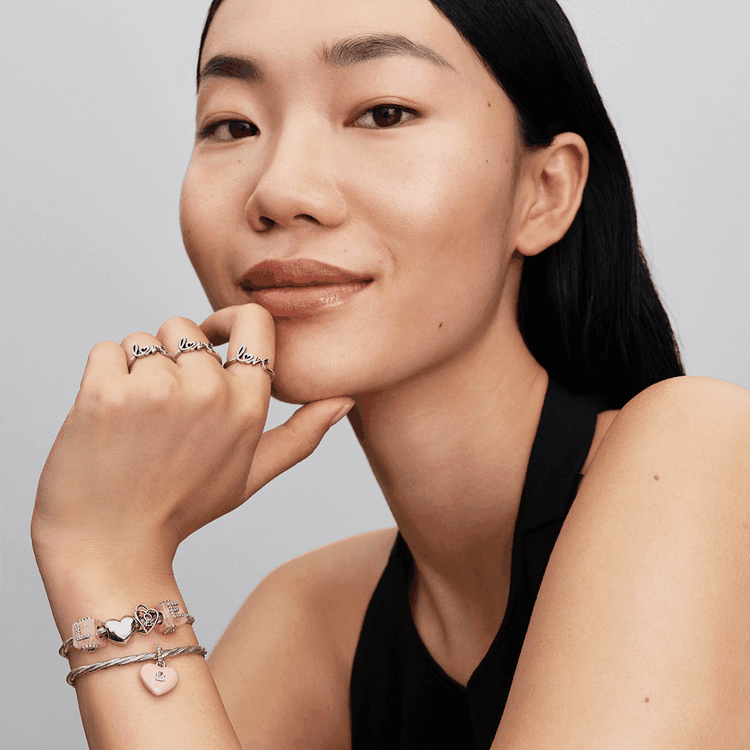 Pandora charm karkötő és love gyűrűk Pandora charm karkötő szív motívumokkal és feliratos gyűrűk viselve, finom romantikus stílusban